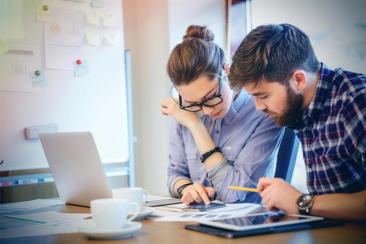 Two people reviewing documents and notes together at a desk
